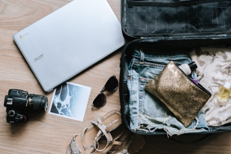 Open suitcase with clothes, camera, and travel items prepared for a vacation trip